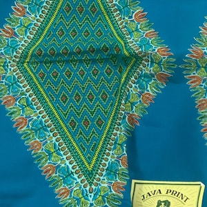 Puede incluir: Tela de color turquesa con un gran patrón en forma de diamante en diseños florales verdes, amarillos y rojos. La tela tiene una etiqueta "Java Print" en la esquina inferior derecha, que indica un diseño registrado.