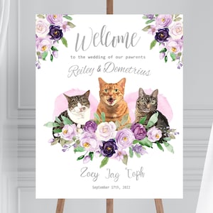 May include: A wedding welcome sign with a floral design and three cats. The sign reads "Welcome to the wedding of our pawrents Reiley & Demetrius Zoey Jag Toph September 17th, 2022".
