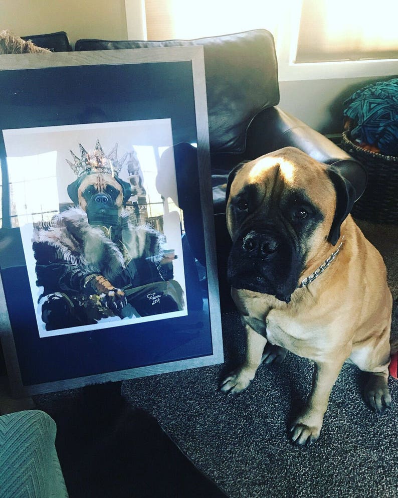 May include: A framed illustration of a dog wearing a crown and fur-trimmed robe, sitting on a throne. A large brown dog is sitting in front of the frame.