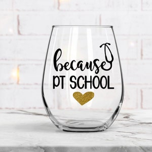 May include: A clear stemless wine glass with the text "because PT SCHOOL" in black script and a gold glitter heart. A stethoscope graphic is incorporated into the word "because". The glass is on a white marble surface.