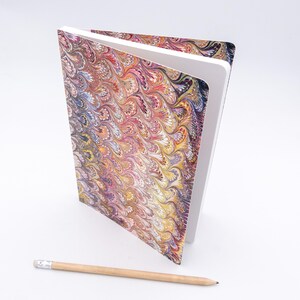May include: A closed notebook with a marbled cover in shades of pink, yellow, blue, and brown. The cover has a swirling pattern.