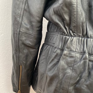 K&ouml;nnte beinhalten: Schwarze Lederjacke mit Rei&szlig;verschlussdetail am &Auml;rmel und einer taillierten Taille.