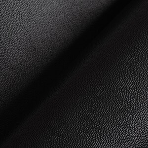 May include: Close-up of black textured leather with a subtle sheen. The leather has a pebbled surface and is folded in half.
