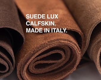 May include: Close-up of three rolls of brown suede leather. The text "SUEDE LUX CALFSKIN. MADE IN ITALY." is printed on the leather.