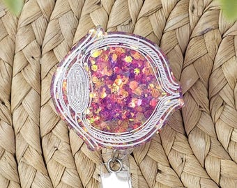 Porta-crachá retrátil em formato de olho com glitter, para optometria.