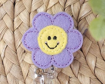 Porta credencial retráctil con diseño de flor sonriente de lavanda, ideal para enfermeras pediátricas y docentes.