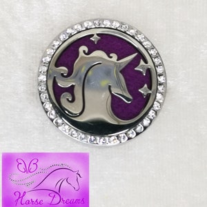 Könnte beinhalten: Ein silberfarbener Autodiffusor mit violettem Hintergrund und einer Unicorn-Silhouette. Der Diffusor ist von einem Ring aus klaren Strasssteinen umgeben.