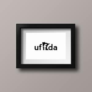 May include: Black and white framed print with the word "uffda" in a stylized font, with the letter "f" replaced by the outline of the state of Minnesota.