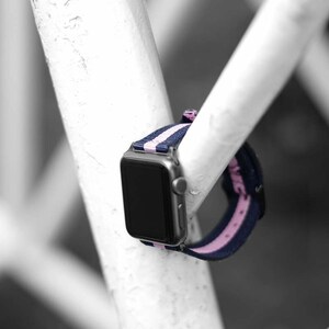 May include: A black and pink striped watch band with a silver watch face.