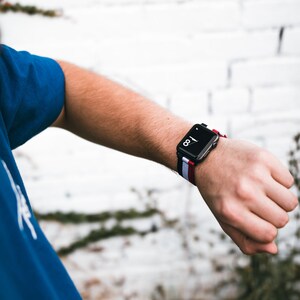 May include: A black smartwatch with a white and red striped band. The watch face displays the time as 1:08.
