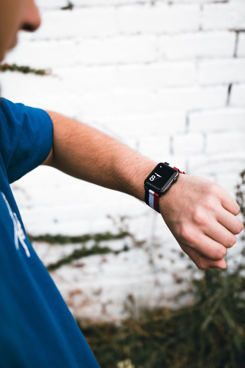 May include: A black smartwatch with a white and red striped band. The watch face displays the time as 1:08.