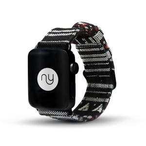以下が含まれることがあります： 黒と白のストライプのApple Watchバンドに赤と白のパターンが施されています。バンドは織り生地製で、黒いバックルが付いています。