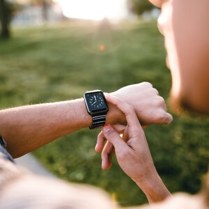 以下が含まれることがあります： 手首にストライプのバンドが付いた黒いスマートウォッチをしている人。時計の文字盤は時間を示しています。