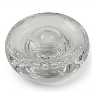 Puede incluir: Un cuenco de cristal transparente de forma circular con un borde grueso y liso y una cúpula central elevada. El diseño crea una serie de hendiduras concéntricas y onduladas en el cristal, lo que resulta en un aspecto transparente y reflectante.