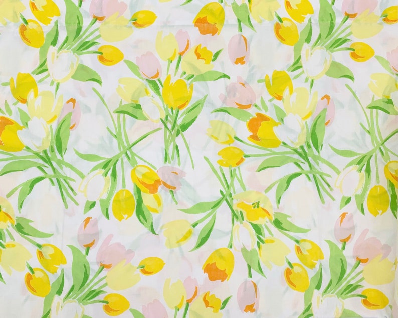 May include: A white fabric with a repeating pattern of yellow and pink tulips. The tulips are stylised and have a simple design.