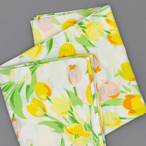May include: Two white fabric panels with a floral pattern of yellow, orange, and pink tulips on a green stem. The fabric is folded in half and the pattern is repeated on both sides.