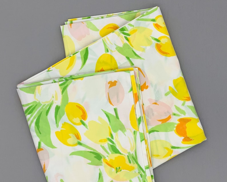 May include: Two white fabric panels with a floral pattern of yellow, orange, and pink tulips on a green stem. The fabric is folded in half and the pattern is repeated on both sides.