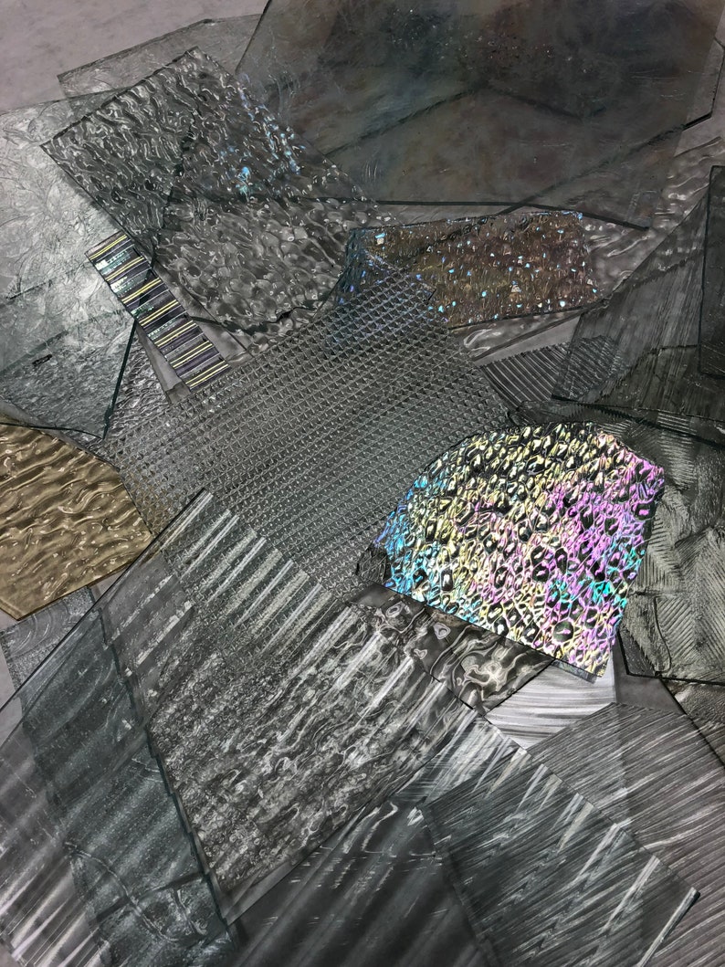 May include: A collection of textured glass sheets in various shades of gray, with one sheet featuring a rainbow iridescent pattern.