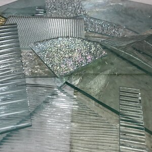 May include: A collection of different textured glass panels, including ribbed, patterned, and frosted glass. The panels are arranged in a random pattern, creating a visually interesting display.
