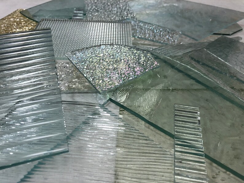 May include: A collection of different textured glass panels, including ribbed, patterned, and frosted glass. The panels are arranged in a random pattern, creating a visually interesting display.