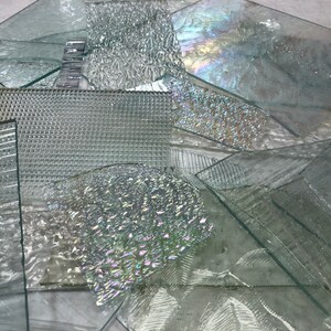 May include: Assortment of clear glass sheets with various textures, including a grid pattern, wavy, and iridescent.