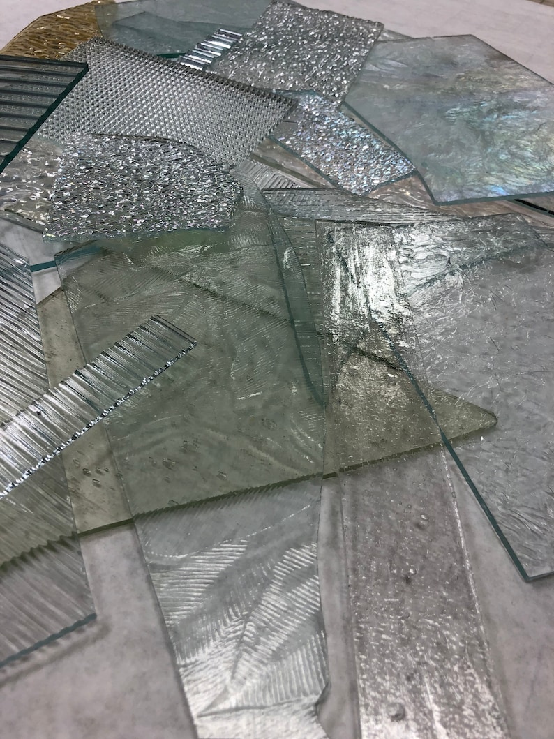 May include: A collection of clear glass sheets with various textures, including ribbed, textured, and smooth. The glass sheets are arranged in a random pattern.