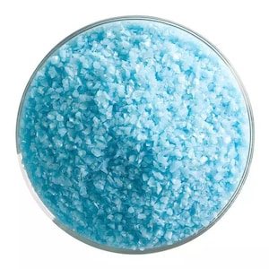 May include: A close-up view of a glass bowl filled with light blue iridescent glass glitter.