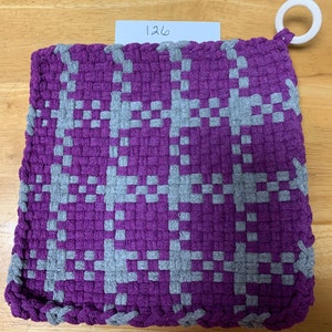 May include: Purple and gray woven pot holder with a loop handle. The pot holder has a checkered pattern.
