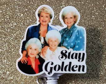May include: A white retractable badge holder with a colorful image of four women and the text "Stay Golden".