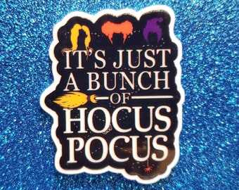 May include: A black and white sticker with the text "IT'S JUST A BUNCH OF HOCUS POCUS". The sticker features illustrations of three witch hairstyles, a broom, and a spider. The background is a sparkly blue.