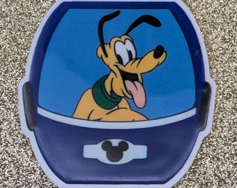 May include: A Pluto sticker featuring the Disney cartoon dog in a blue and white vehicle. Pluto is yellow with black ears and a green collar. The sticker has a white border and a Mickey Mouse icon.
