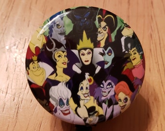 May include: A round, colorful button with images of various Disney villains, including Maleficent, Ursula, and Cruella de Vil. The button is attached to a black retractable badge holder.