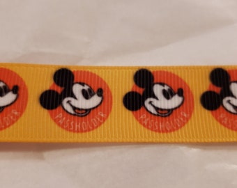 May include: Yellow ribbon with repeating images of Mickey Mouse's face in orange circles. The text "Passholder" is printed in each circle.