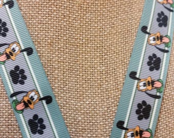 May include: A teal blue lanyard with a white stripe and a repeating pattern of paw prints and cartoon Goofy dogs.
