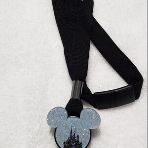 May include: Black lanyard with a retractable badge holder featuring a silver glitter Mickey Mouse head with a silhouette of Cinderella's castle inside.