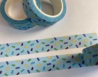 May include: Two rolls of light blue washi tape with a confetti pattern of yellow, green, blue, and purple shapes. A strip of the same tape is unrolled below the rolls, showing the pattern. The tape is designed for crafts and decorative purposes.