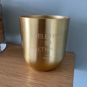 Peut inclure: Un pot de bougie en métal doré avec le texte "MELCHIOR & BALTHAZAR PARIS" gravé sur le devant.