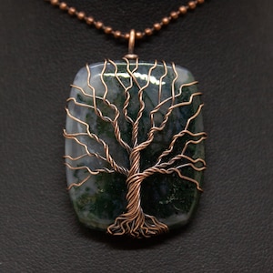 May include: A copper wire tree of life pendant featuring a green and grey agate stone. The pendant is on a copper chain.