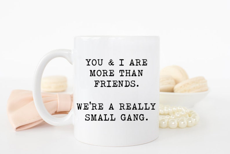 May include: White ceramic coffee mug with black text that reads "You & I are more than friends. We're a really small gang."