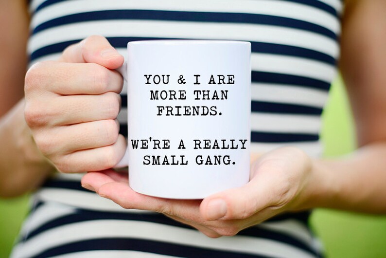 May include: White ceramic mug with black text that reads "You & I are more than friends. We're a really small gang."