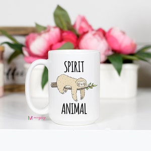 May include: White ceramic coffee mug with a black and white illustration of a sloth hanging from a branch. The text "SPIRIT ANIMAL" is printed on the mug.
