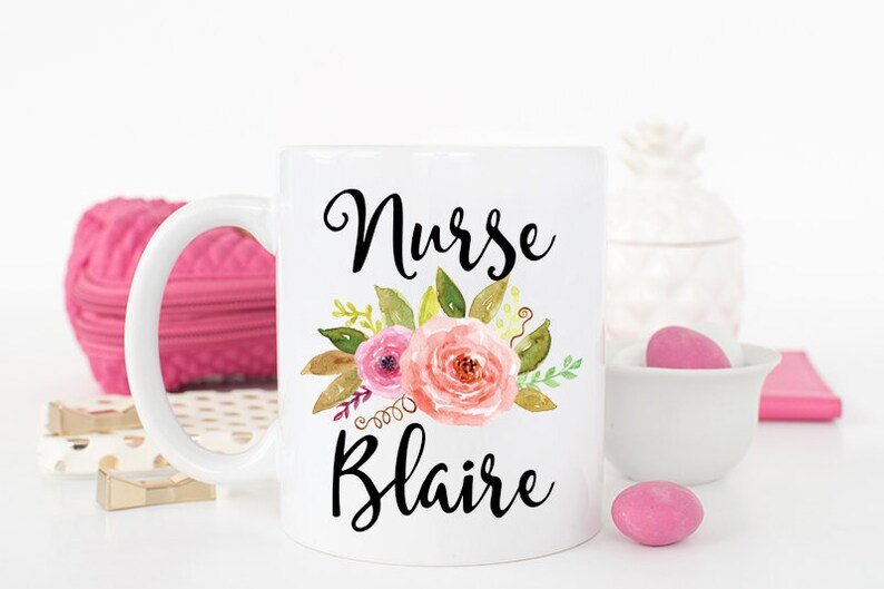Puede incluir: Taza de cer&aacute;mica blanca con un dise&ntilde;o floral negro y el texto "Nurse Blaire".