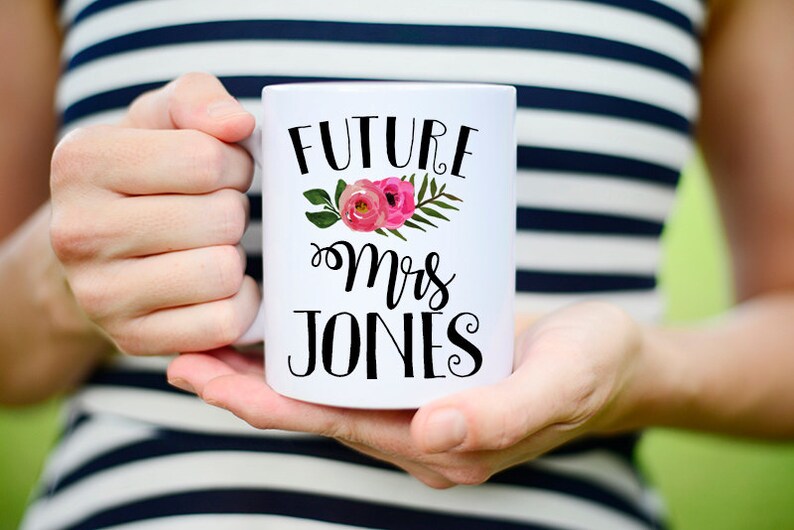 May include: White ceramic mug with black text that reads "Future Mrs. Jones" and a pink floral design.