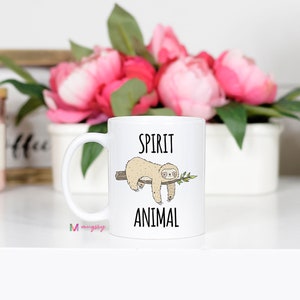 May include: White ceramic coffee mug with a black and white illustration of a sloth hanging from a branch. The text "Spirit Animal" is printed on the mug.