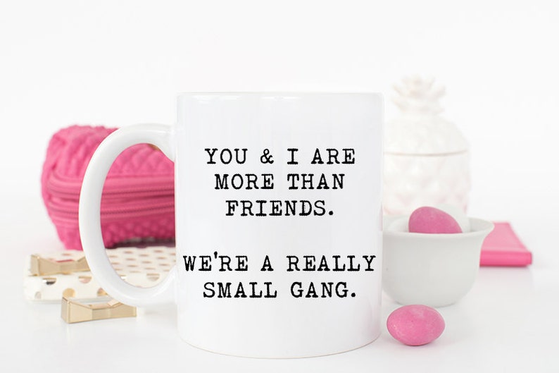 May include: White ceramic coffee mug with black text that reads "You & I are more than friends. We're a really small gang."