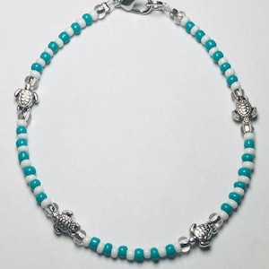May include: A turquoise and white beaded anklet with four silver turtle charms.