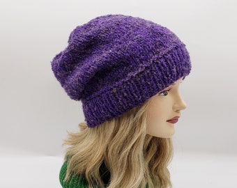 May include: A purple slouchy beanie hat with a textured knit. The hat is made of a soft, warm material and has a slouchy fit.