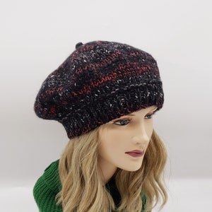 May include: A black, red, and white knit beret with a textured pattern.