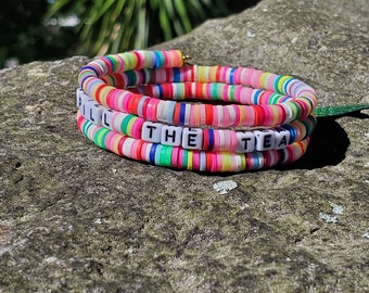 May include: Multicolored beaded bracelet with the words "Spill the Tea" spelled out in white letters.