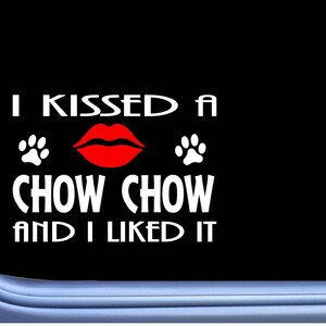 May include: A black and white car window sticker with the text "I kissed a Chow Chow and I liked it". The text is in white with a red lip print and two paw prints.